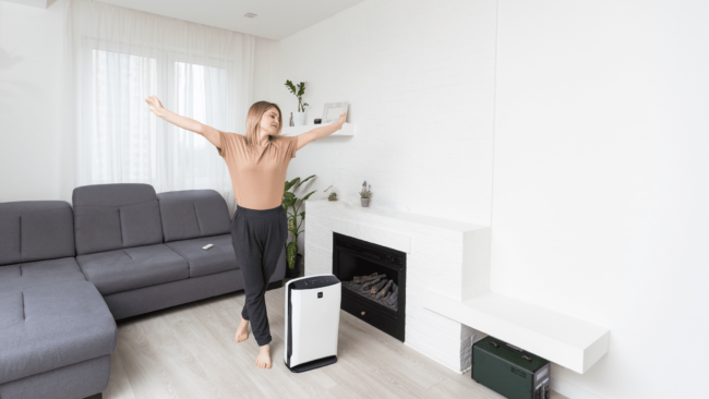 Woman stretching in living room in front of portable AC unit