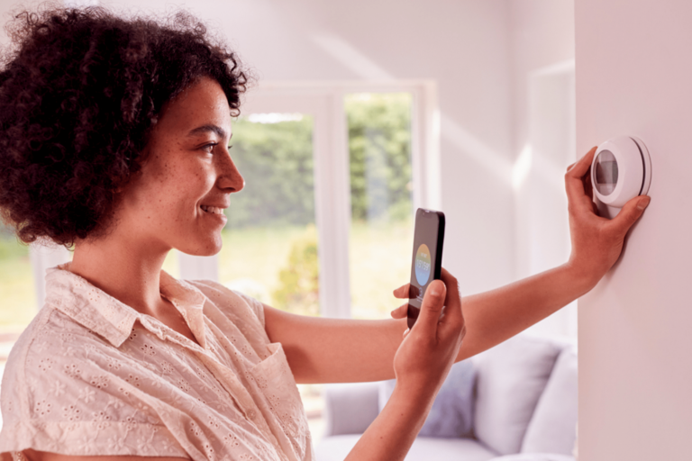 Women adjusting smart thermometer with phone